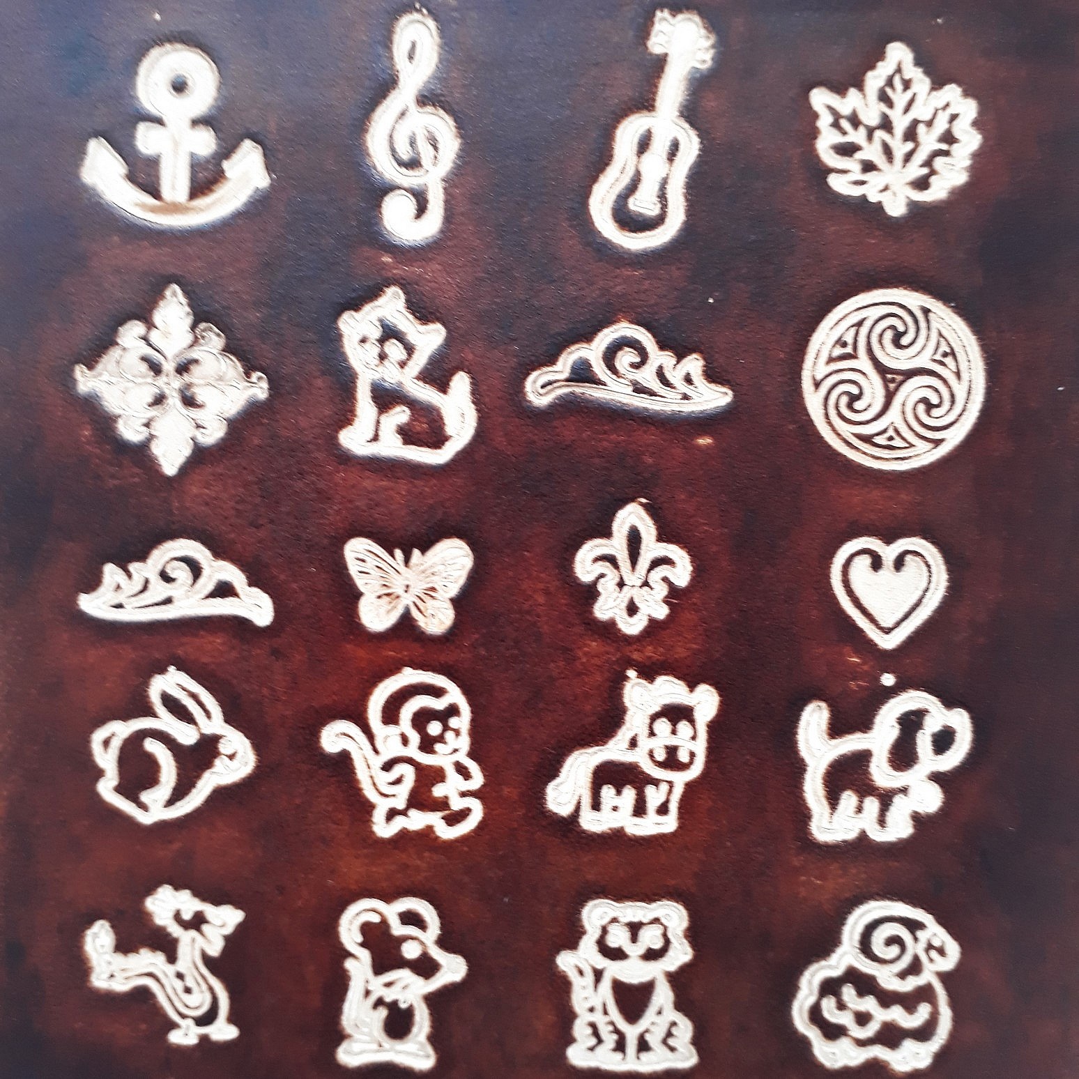 Motifs variés gravés sur une plaque de cuir marron.