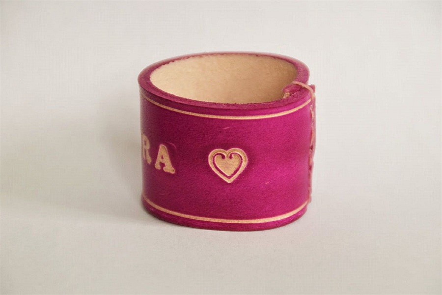 Bracelet en cuir rose gravé avec un motif cœur.